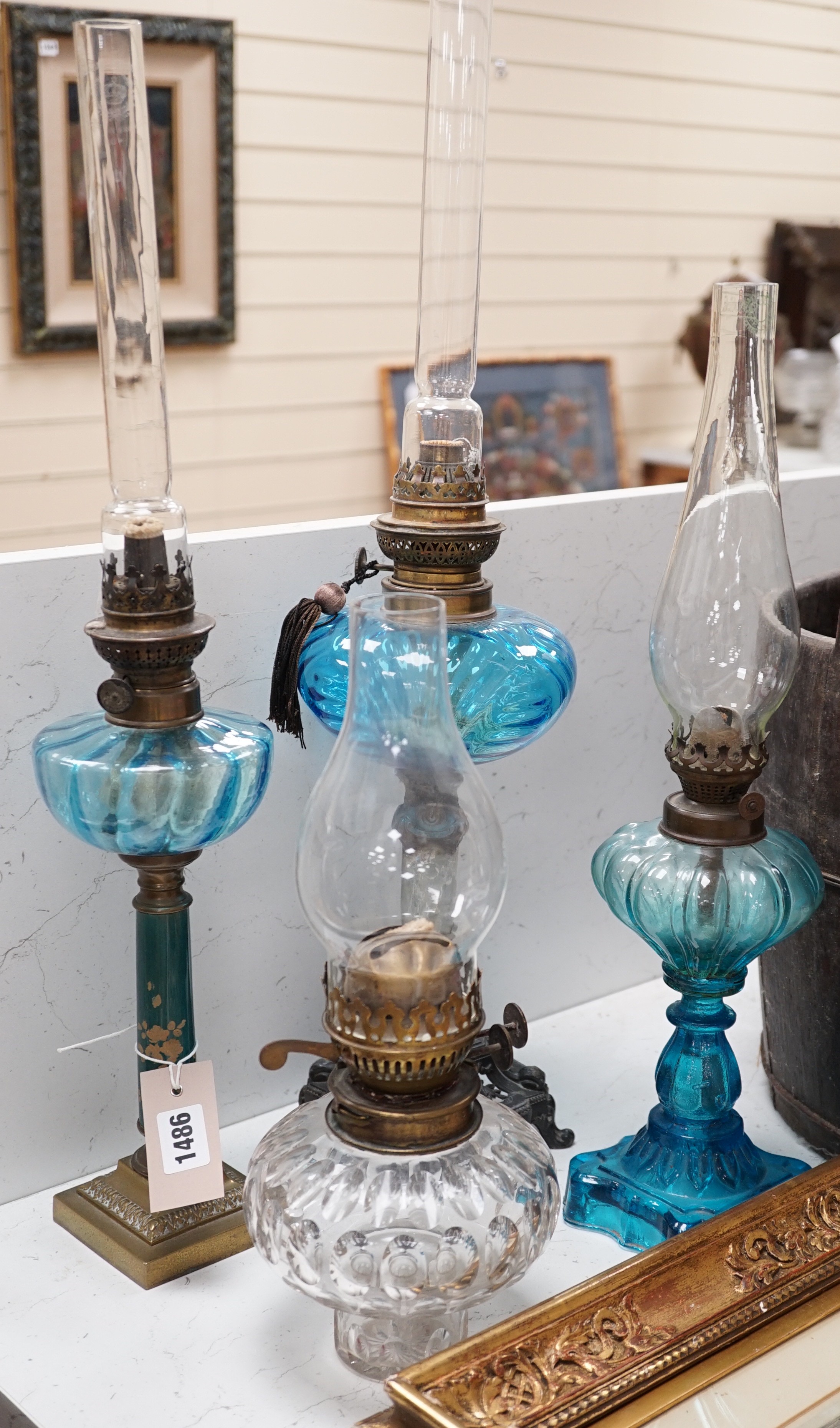 Three blue glass oil lamps and a clear glass oil lamp, tallest 62cms high